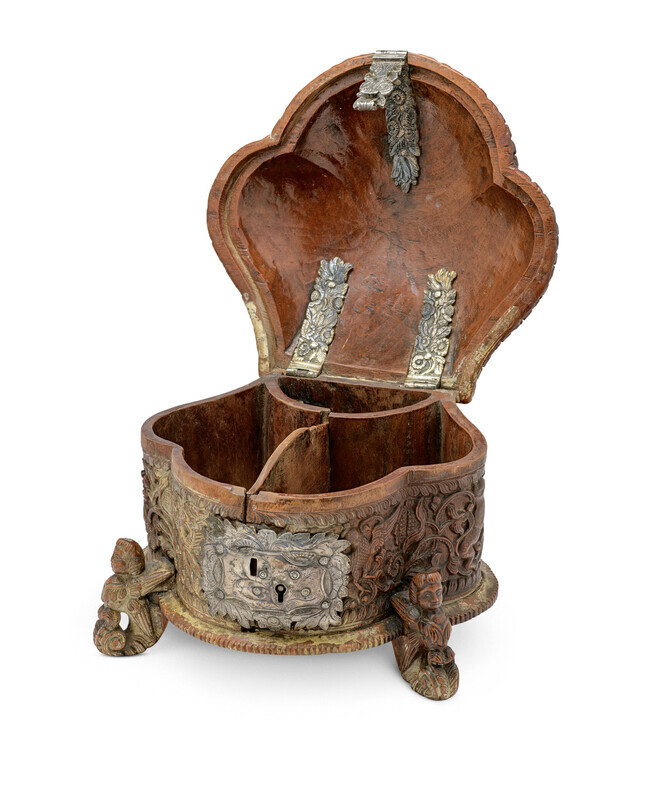 Ornate wooden box in the shape of a shell with detailed carvings, metal lock, and three small feet shaped like mythical creatures, photographed open on a white background.