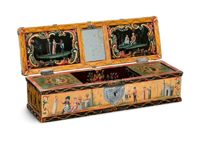 An ornate, rectangular wooden box with hand-painted scenes in imitation lacquer, a central lock, two small interior compartments, and a mirror on the inside of the lid photographed on a white background. The hand-painted scenes depict willow trees, scenes of courtship, charity, battle, and portraits of fashionable men and women. 
