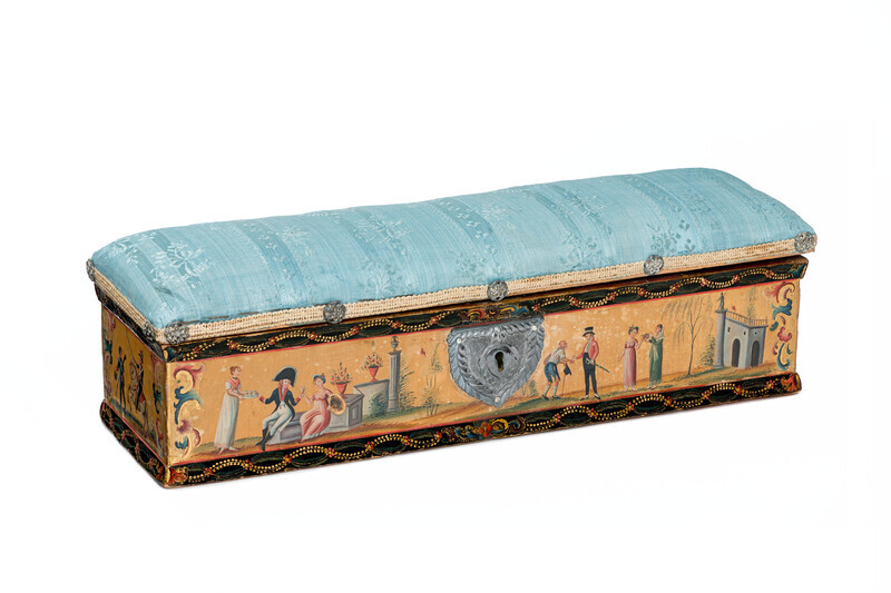 An ornate, rectangular wooden box with hand-painted scenes in imitation lacquer topped by a blue silk pin cushion and photographed on a white background. The hand-painted scenes depict willow trees, scenes of courtship, charity, and battle.