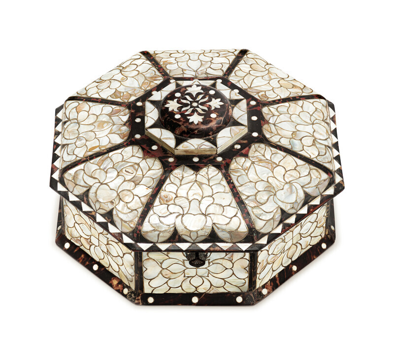 Octogonal box with ornate mother-of-pearl inlay in an abstract floral pattern framed by tortoiseshell, photographed on a white background and viewed from slightly above. 