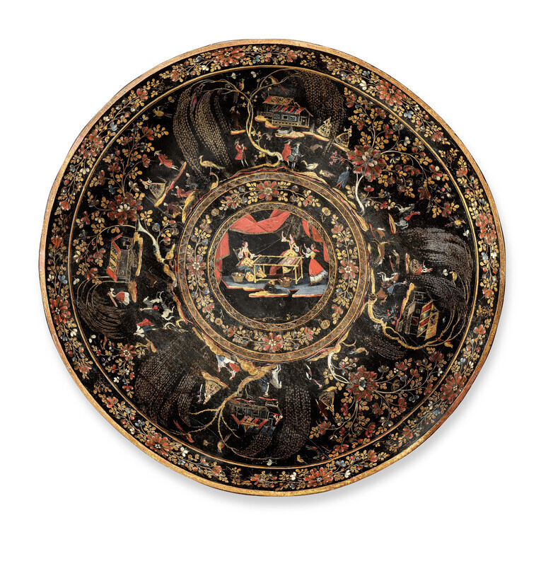 Multi-colored circular tray in imitation-lacquered wood viewed from above. It includes a central medallion with the Greek myth of Arachne and Athena, surrounded by vignettes of regional daily life all on a black background with gold inlay. Object is photographed on a white background. 