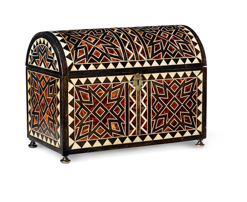 Wooden casket with tortoiseshell and bone inlay in abstract geometric patterns and iron fittings and flared iron feet. Photographed on a white background.