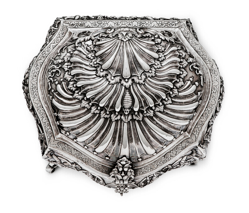 Top view of ornate silver box in the shape of a shell, photographed on a white background.