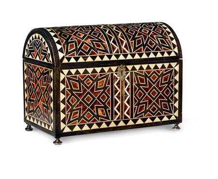 Wooden casket with tortoiseshell and bone inlay in abstract geometric patterns and iron fittings and flared iron feet. Photographed on a white background.