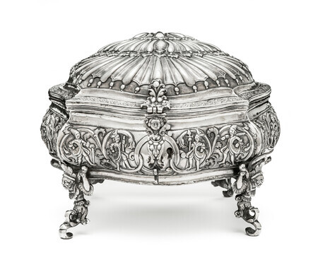 Ornate silver box in the shape of a shell, viewed head on, with hunting fingures on the base and mythical creatures serving as the feet and lock. Photographed on a white background.